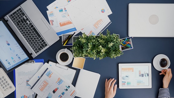 Top view of businesswoman analyzing financial graphs statistics drinking coffee while working in startup company office. Manager woman developing management strategy brainstorming ideas